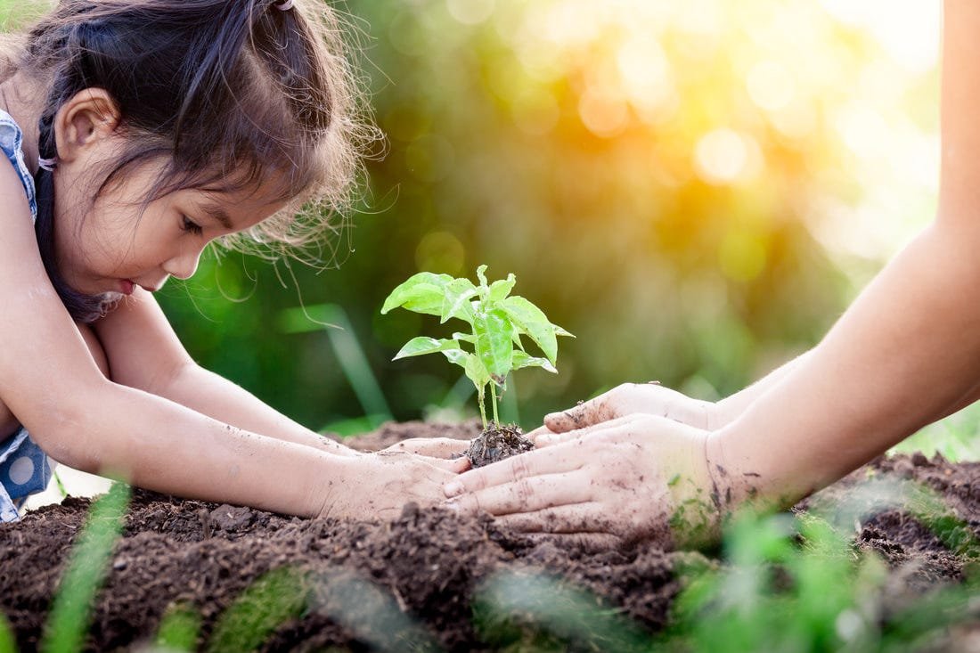 Een moeder en kind planten samen een plant in de aarde.